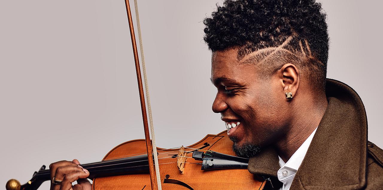 Profile of Edward Hardy holding a violin and smiling