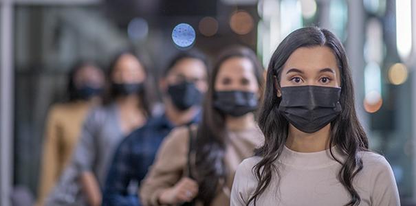 College 学生 standing in a hallway wearing face masks