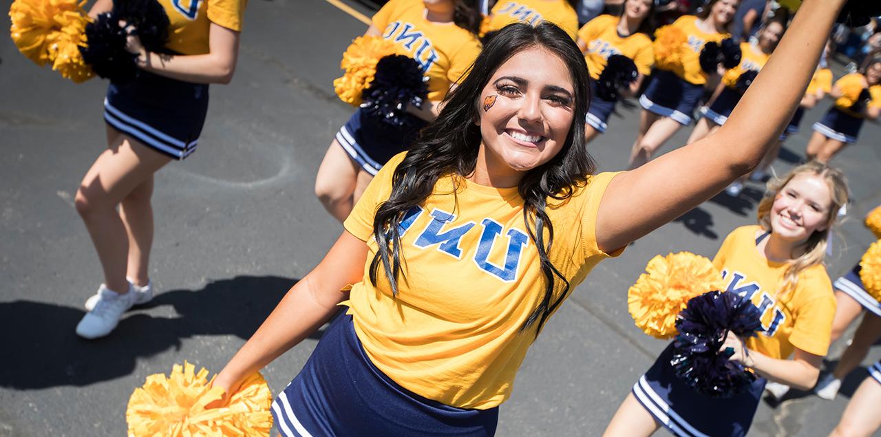 A UNC cheerleader smiling and holding up a pom pom