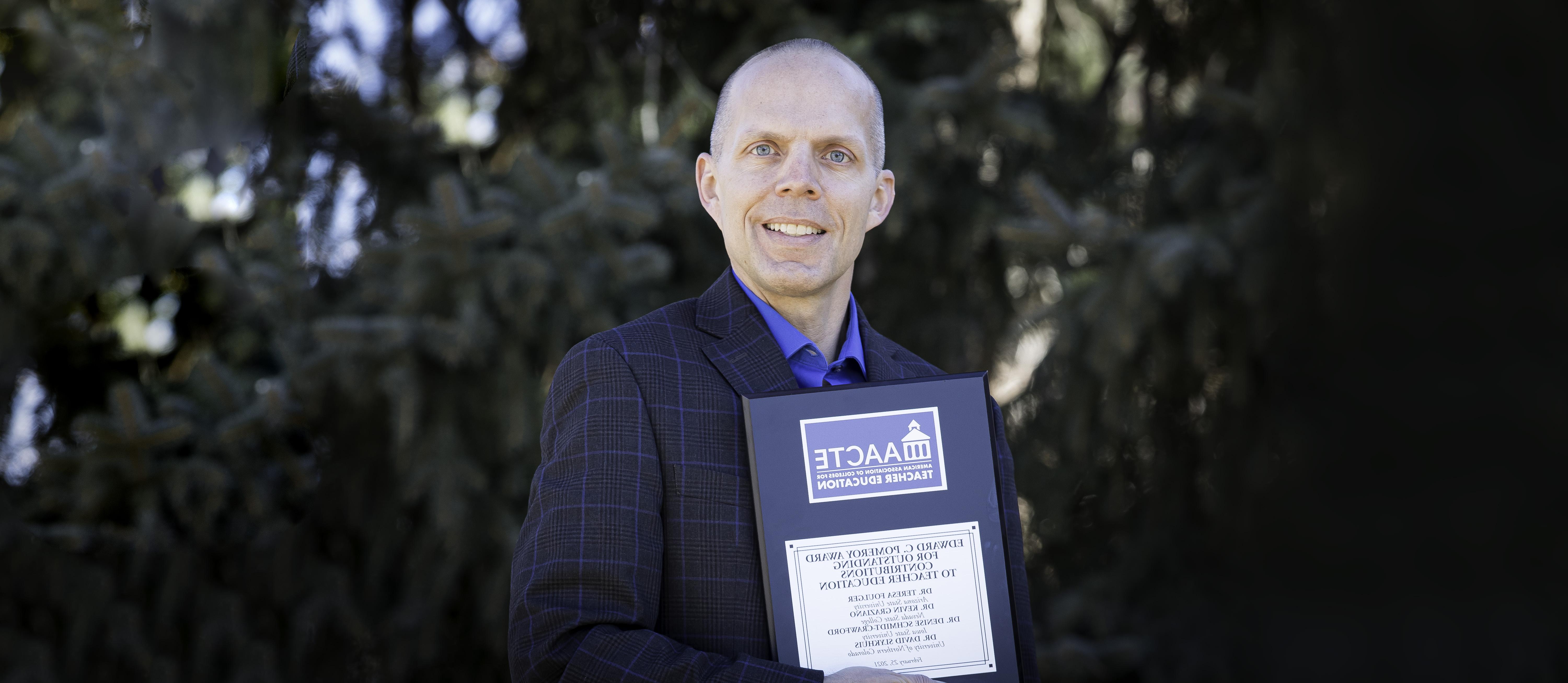 David holding the award plague on campus